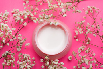 Obraz na płótnie Canvas Cream for face in flowers . Face cream on a pink background. Skin care. The beauty industry. Copy space. White flowers. Article about the right choice of cream. Selection of the cream. Spa treatments.