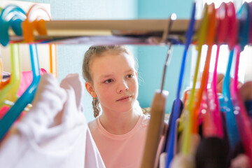 Portrait of a pretty teen girl looking through the wardrobe with clothing