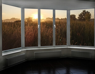 Window with view to dawn over field. Sunrise and landscape through window