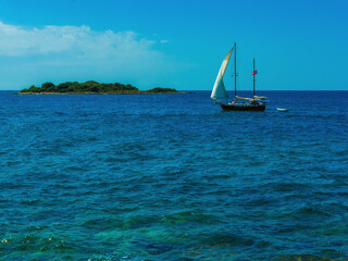 a sailboat in the sea sails along the island