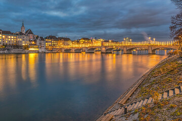 Fototapeta na wymiar Mittlere bridge over Rhine river and city skyline at sunset Basel Switzerland