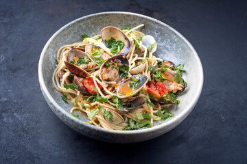 Spaghetti alle vongole with tomato in seafood jus served as close-up at a Nordic design bowl with copy space