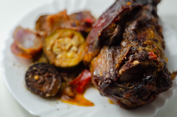 Bacon joint with bone served with grilled vegetables, red and yellow peppers, zucchini and red onion