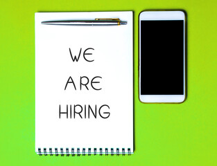 Notebook with the inscription We are hiring, a pen and a telephone. Employee Search. Attraction to work. Human Resource Management. Hire. Promotion. Working staff. Business concept