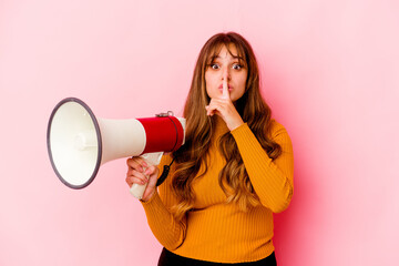 Young caucasian woman holding a megaphone isolated keeping a secret or asking for silence.