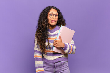 young hispanic woman looking puzzled and confused, biting lip with a nervous gesture, not knowing...