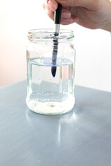 A clear jar of water for diluting the watercolor paint and washing the brush. Space for text