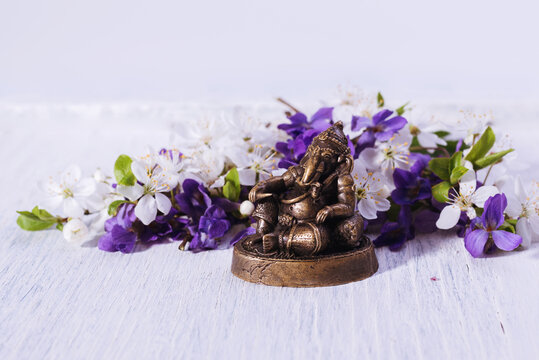 Ganesh, hindu god of success. Little statue of bronze Ganesha against floral background. Happy Ganesh Chathurthi backdrop.