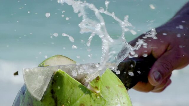 Opening coconut with machete in slow motion, close-up.