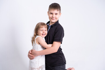 handsome older brother teenager hugging his cute little sister on white background
