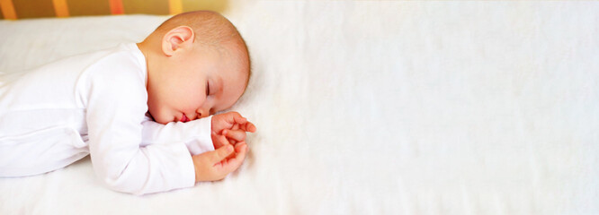 Banner Portrait of a Cute Infant Baby Boy 5 Months Old in white clothes, Sleeping in his Crib. Childhood Dreams. Concept of Health and Children. Selective focus.