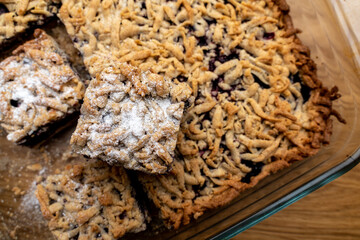 Sliced homemade grated berry pie, in a glass baking dish on a wooden board. Homemade cakes.