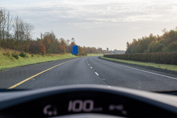 Driving a car on motorway. View from drivers seat. Road sign ahed.