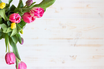 Pink and yellow tulips on white wood background with copy space