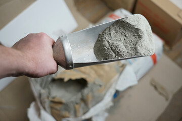 Scoop with cement next to the bag. Preparation of cement and glue mortar