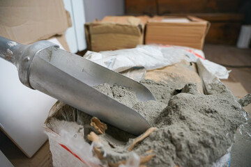 Scoop with cement next to the bag. Preparation of cement and glue mortar