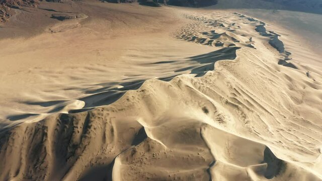 Eureka dunes at Death Valley nature park on sunny winter day with blue sky above. Scenic mountain landscape, desert 4K. Sand dunes aerial with high snow summit and peaks on motion background