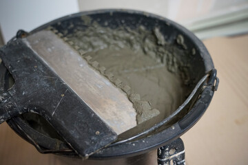 Spatula in a bucket of tile adhesive. Laying tiles at home