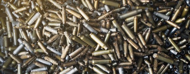 Empty carbine or rifle cartridges. A large number of cases. Background of brass ammunition cartridges to illustrate armed conflict, war or shooting