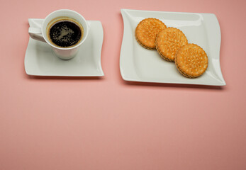 cup of coffee with cookies on a pink background