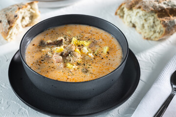 Cream cheese soup with mushrooms and potatoes, delicious first course in black bowl on the white table, top view horizontal