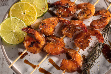 A plate with homemade fried shrimp skewers with garlic, lemon and herbs, top view with selective focus
