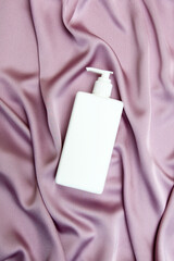 Blank label cosmetic container bottle as product mockup on pink silk background, hygiene and healthcare