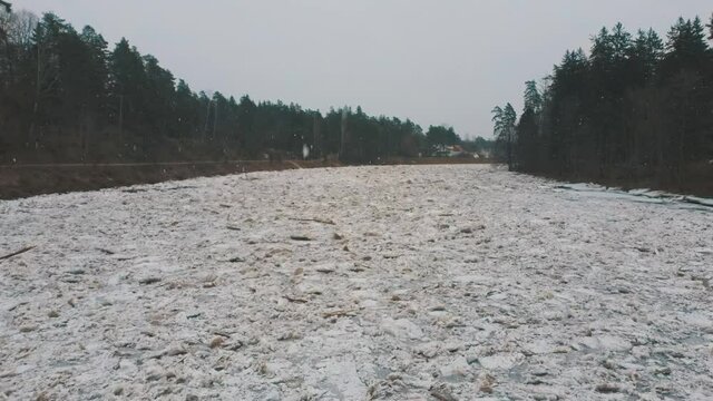 Huge Ice Loads Drift in the River Ogre, Latvia. Aerial Dron Shot in Snowy Mart Day. Congestion on the River in the Spring. A Large Cluster of Moving Ice Blocks
