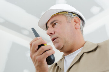 mature foreman talking into walkie talkie