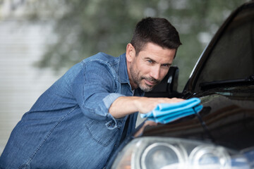 handsome man is washing car outdoor