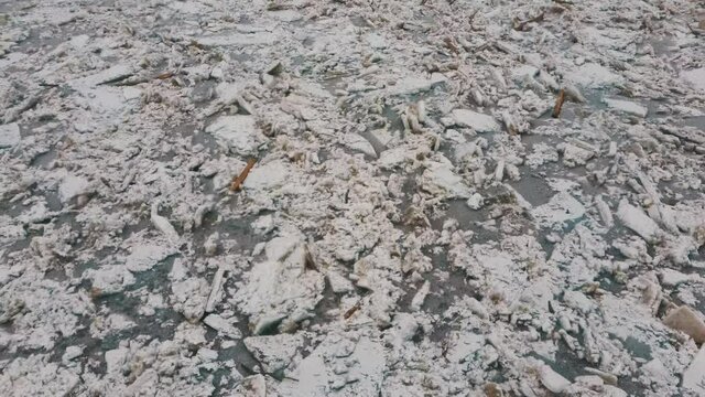 Huge Ice Loads Drift in the River Ogre, Latvia. Aerial Dron Shot in Snowy Mart Day. Congestion on the River in the Spring. A Large Cluster of Moving Ice Blocks