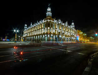 Fototapeta na wymiar Cuba classic dance school at night illuminated and a car crossing the road leaving a beam of light
