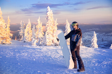 Snowboarder woman with snowboard stands on ski lift snow mountains sunset