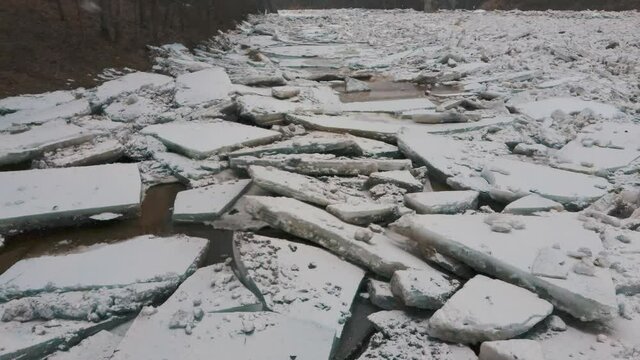 Huge Ice Loads Drift in the River Ogre, Latvia. Aerial Dron Shot in Snowy Mart Day. Congestion on the River in the Spring. A Large Cluster of Moving Ice Blocks