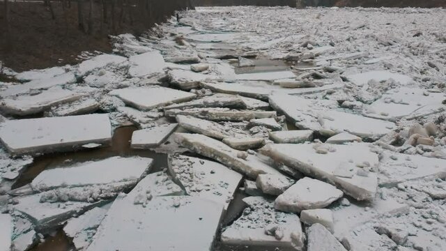 Huge Ice Loads Drift in the River Ogre, Latvia. Aerial Dron Shot in Snowy Mart Day. Congestion on the River in the Spring. A Large Cluster of Moving Ice Blocks