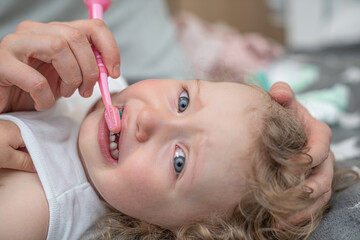 Obraz na płótnie Canvas Mom brushes the teeth of the child.