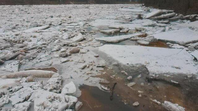 Huge Ice Loads Drift in the River Ogre, Latvia. Aerial Dron Shot in Snowy Mart Day. Congestion on the River in the Spring. A Large Cluster of Moving Ice Blocks
