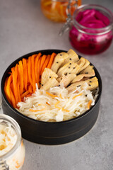 Homemade village fermented sauerkrauts, red cabbage and korean carrot, asparagus. Vegan salad in black ceramic bowl. Probiotics gut health food concept. Supplement and adaptogens. Superfood, top view