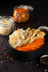 Homemade village fermented sauerkrauts, and korean carrot, asparagus. Vegan salad in black ceramic bowl. Probiotics gut health food concept. Supplement and adaptogens. Superfood, top view