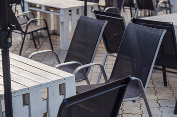 Outdoor cafe interior in the street, with wooden furniture, rotan chairs and creative wooden pallet tables. Selective focus.