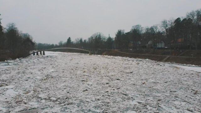 Huge Ice Loads Drift in the River Ogre, Latvia. Aerial Dron Shot in Snowy Mart Day. Congestion on the River in the Spring. A Large Cluster of Moving Ice Blocks