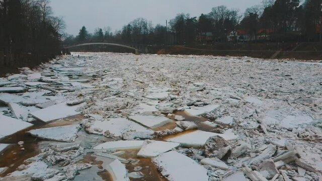 Huge Ice Loads Drift in the River Ogre, Latvia. Aerial Dron Shot in Snowy Mart Day. Congestion on the River in the Spring. A Large Cluster of Moving Ice Blocks