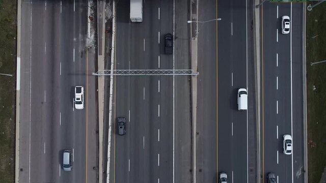 2.7K aerial shot running parallel to 12 lanes of highway 401 traffic with a flyover lane crossing highway
