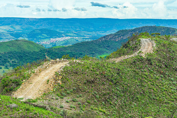 Fototapeta na wymiar Dirt road on top of the hill surrounded by green nature. Landscape of Capitólio MG, Brazil. Minas Gerais state.