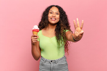 young hispanic woman smiling and looking friendly, showing number three or third with hand forward,...