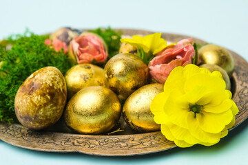Obraz na płótnie Canvas Easter decoration. Dish with Easter golden painted eggs and spring flowers.