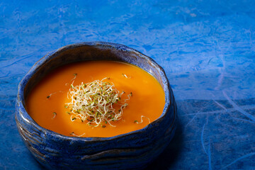 Pumpkin cream with germinated seeds on blue background