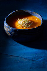 Pumpkin cream with germinated seeds on blue background