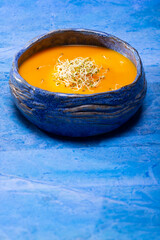 Pumpkin cream with germinated seeds on blue background