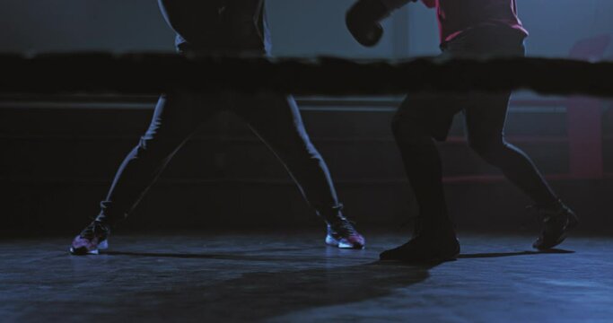 Male fighters are fighting in a dark ring, training. Fighters legs in motion, fight in the ring. Bottom view of the camera. 4k, ProRes